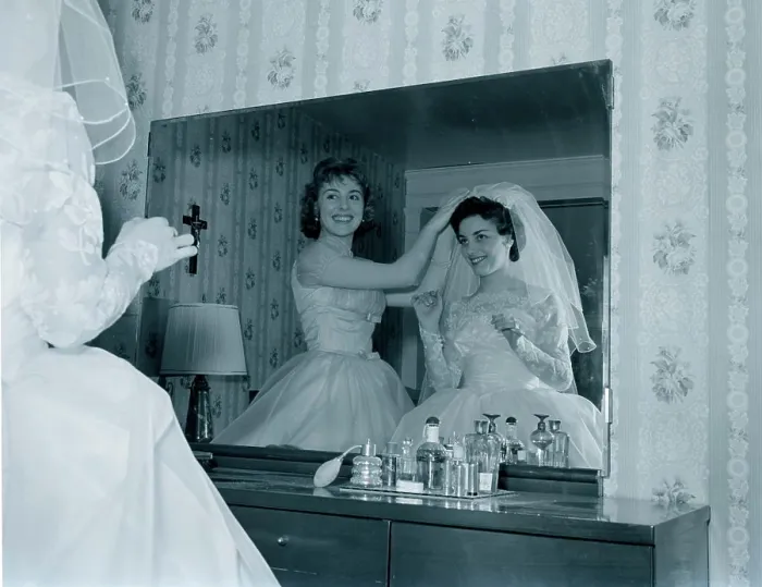 Framed Print : Bridesmaid attaching veil to bride's hair in front of mirror