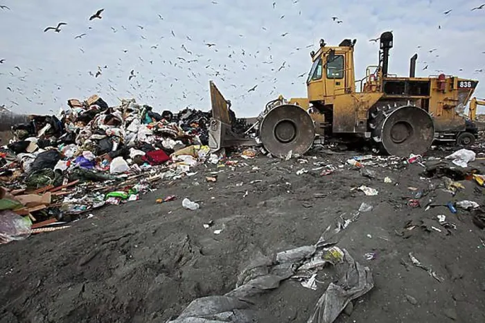 Framed Print : A bulldozer levels and compacts garbage at St