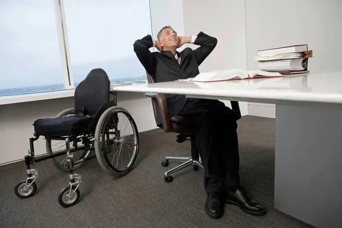 Framed Print : Businessman with a wheelchair relaxing in office Framed Print : Businessman with a wheelchair relaxing in office