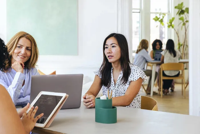 Framed Print : Businesswoman holding ipad discussing strategy with female colleagues Framed Print : Businesswoman holding ipad discussing strategy with female colleagues