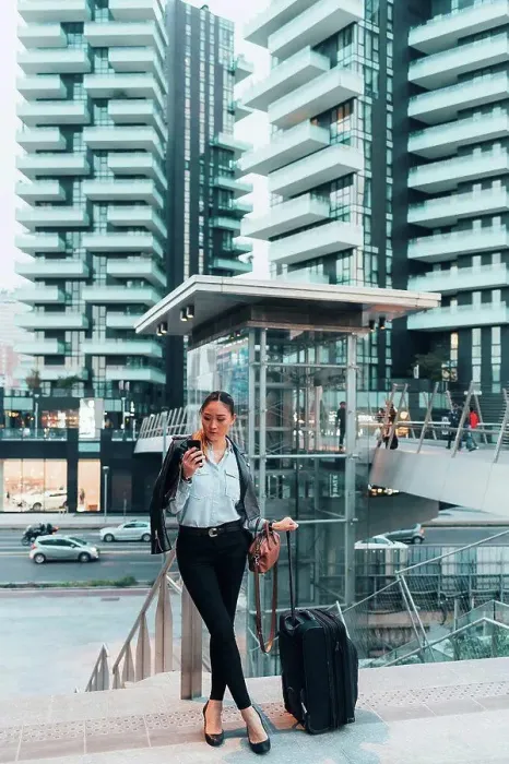 Framed Print : Businesswoman, outdoors, holding wheeled suitcase, using smartphone Framed Print : Businesswoman, outdoors, holding wheeled suitcase, using smartphone