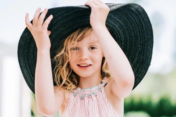 Framed Print : candid portrait of a young girl laughing playing with a large sun hat