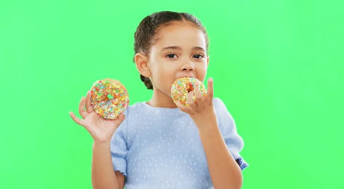 Framed Print : Candy, smile and child eating donuts on green background with cake for party Framed Print : Candy, smile and child eating donuts on green background with cake for party