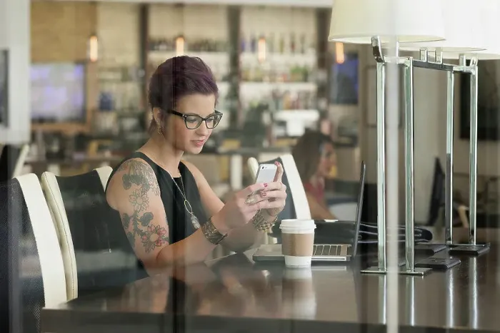 Framed Print : Caucasian woman using cell phone and laptop in coffee shop Framed Print : Caucasian woman using cell phone and laptop in coffee shop