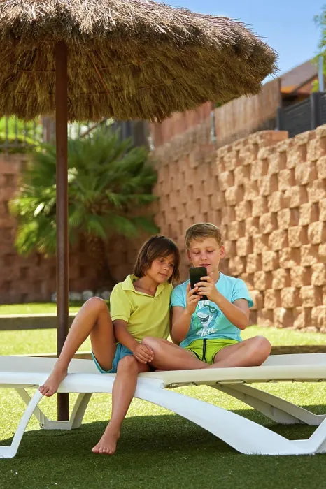 Framed Print : Cheerful boys browsing smartphone on sunbed Framed Print : Cheerful boys browsing smartphone on sunbed