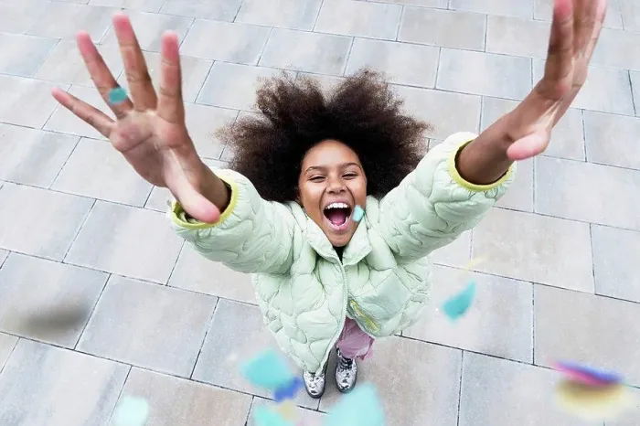 Framed Print : Cheerful girl with arms raised standing amidst confetti falling on footpath Framed Print : Cheerful girl with arms raised standing amidst confetti falling on footpath