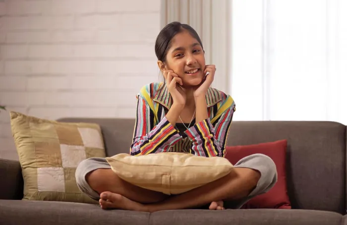 Framed Print : Cheerful girl sitting on sofa and looking at camera with hands on cheek Framed Print : Cheerful girl sitting on sofa and looking at camera with hands on cheek