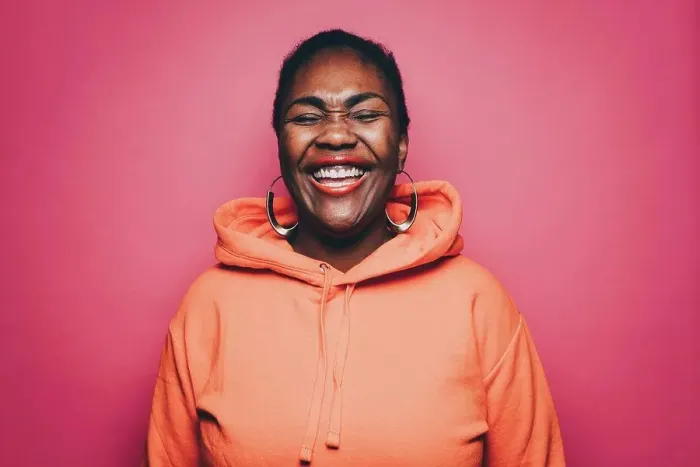 Framed Print : Cheerful mid adult woman wearing orange hooded shirt over pink background Framed Print : Cheerful mid adult woman wearing orange hooded shirt over pink background
