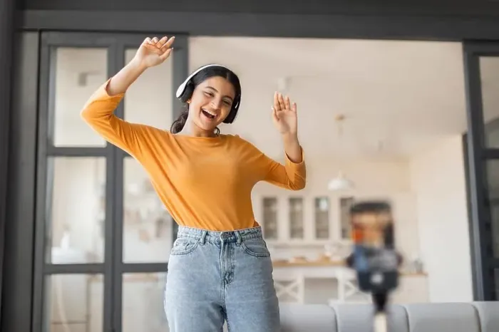 Framed Print : Cheerful young indian vlogger with headphones dancing joyfully while recording video Framed Print : Cheerful young indian vlogger with headphones dancing joyfully while recording video