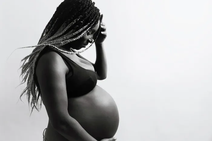 Framed Print : Cheerful young pregnant black female with braids touching belly Framed Print : Cheerful young pregnant black female with braids touching belly