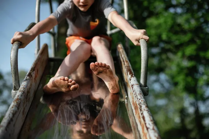 Framed Print : Child's dirty feet sliding down slide on playground at park