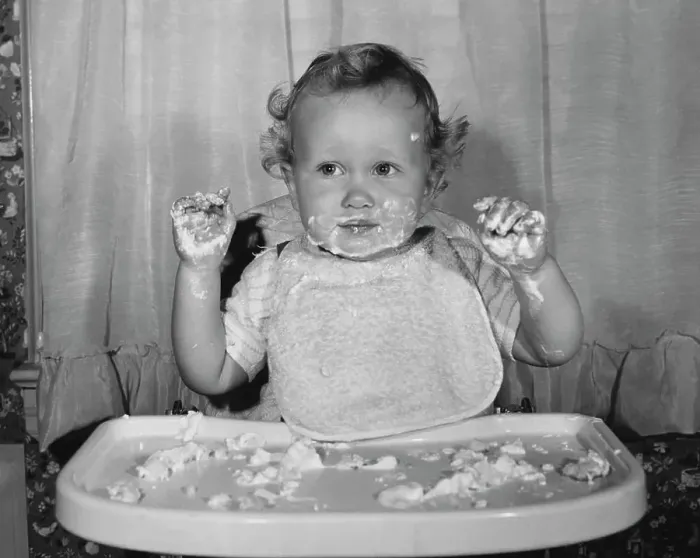 Framed Print : Close-up of a baby sitting in a high chair with food on his face and hands