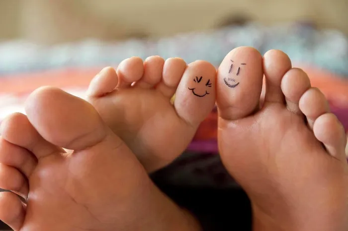 Framed Print : Close-up of bare feet sticking out from covers while couple lays in bed, with smiley faces drawn on big toes Framed Print : Close-up of bare feet sticking out from covers while couple lays in bed, with smiley faces drawn on big toes