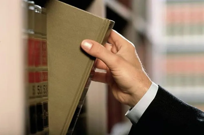 Framed Print : Close-up of a lawyer's hand removing a law book from shelf Framed Print : Close-up of a lawyer's hand removing a law book from shelf