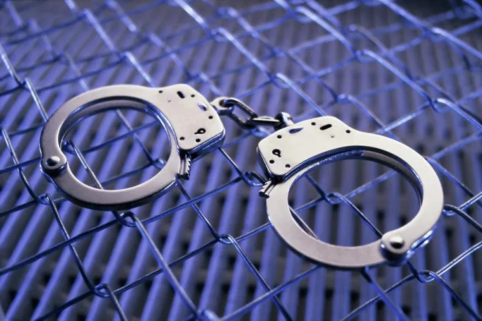 Framed Print : Close-up of a pair of handcuffs on a chain-link fence Framed Print : Close-up of a pair of handcuffs on a chain-link fence