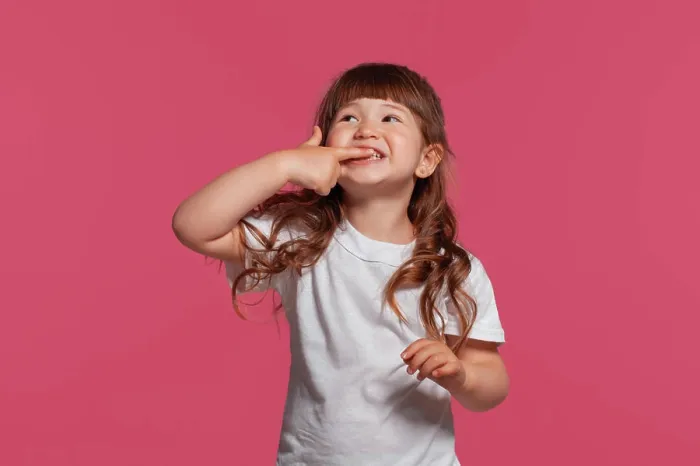 Framed Print : Close-up portrait of a little brunette girl dressed in a white t-shirt posing against a pink studio background