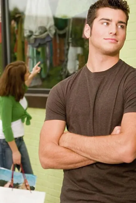 Framed Print : Close-up of a teenage boy looking sideways with a young woman shopping behind him