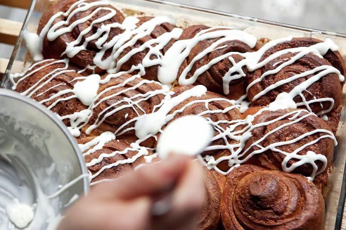 Framed Print : A coffee shop employee putting icing on a cinnamon rolls Framed Print : A coffee shop employee putting icing on a cinnamon rolls