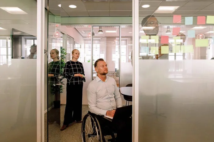 Framed Print : Colleagues looking at businessman sticking adhesive notes on glass wall in board room Framed Print : Colleagues looking at businessman sticking adhesive notes on glass wall in board room