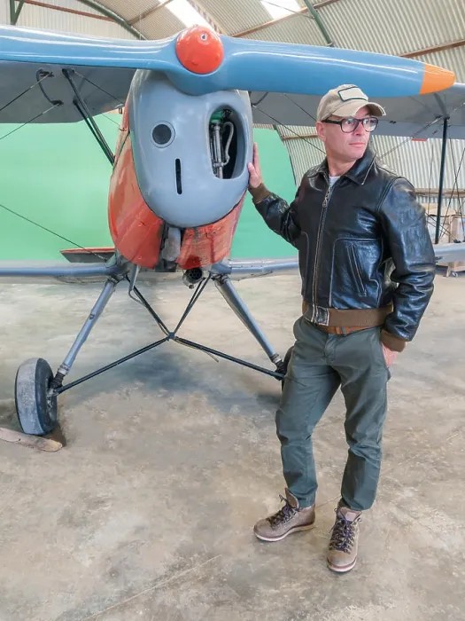 Framed Print : Confident pilot beside retro plane in hangar