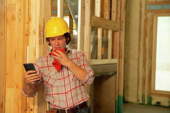 Framed Print : Construction worker on job site feeling ill, sneezing, using mobile phone to check in with tele-medicine doctor Framed Print : Construction worker on job site feeling ill, sneezing, using mobile phone to check in with tele-medicine doctor