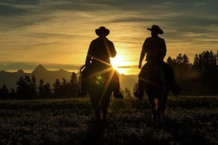 Framed Print : Two cowboys riding across grassland with mountains in background, early morning, British Colombia, Canada
