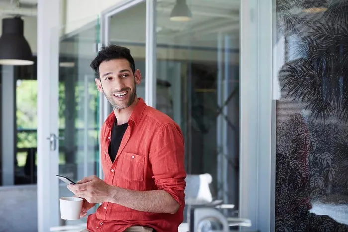 Framed Print : Creative businessman looking away while using mobile phone in office during coffee break