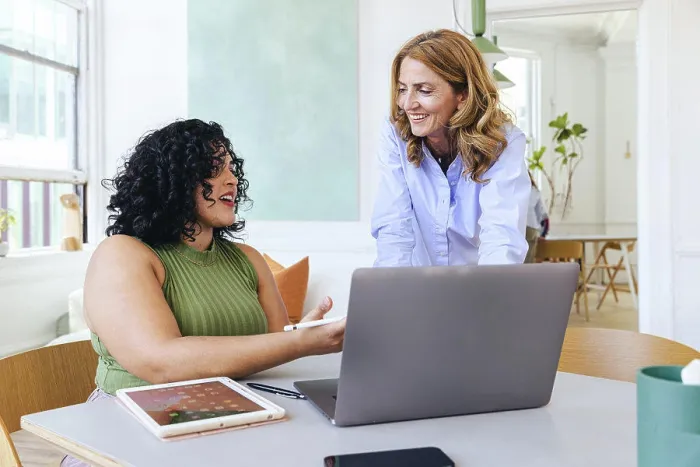 Framed Print : Creative businesswoman explaining smiling colleague over laptop Framed Print : Creative businesswoman explaining smiling colleague over laptop