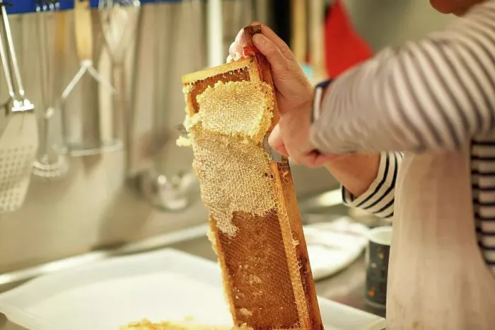 Framed Print : Cropped image of female beekeeper scraping honeycomb in kitchen Framed Print : Cropped image of female beekeeper scraping honeycomb in kitchen