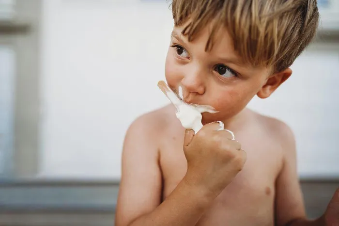 Framed Print : Cute young boy eating ice cream looking to the side outside in summer Framed Print : Cute young boy eating ice cream looking to the side outside in summer
