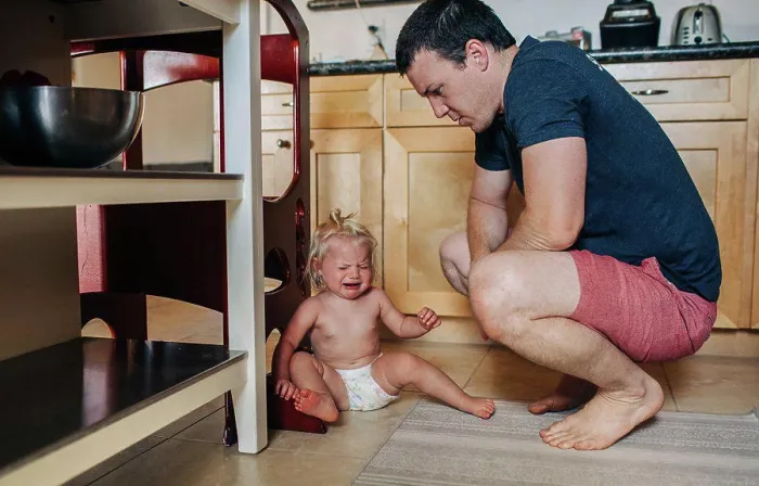 Framed Print : Dad looks down at diapered toddler girl while crying in kitchen Framed Print : Dad looks down at diapered toddler girl while crying in kitchen