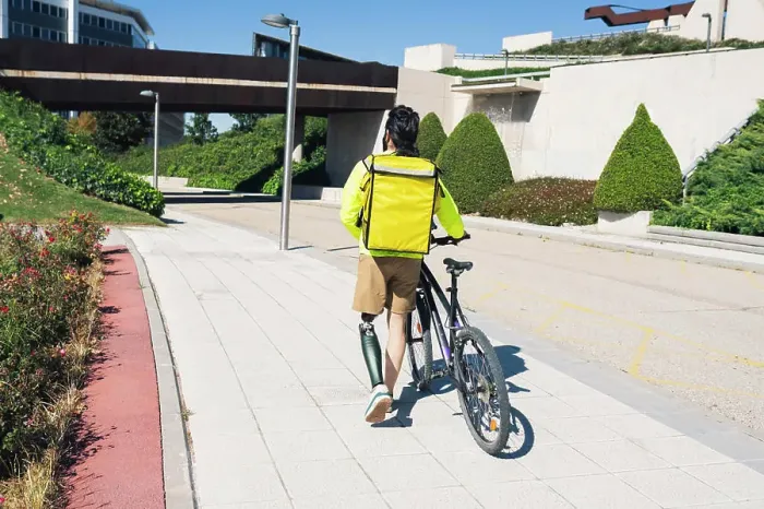 Framed Print : Delivery man with prosthetic leg wheeling bicycle on footpath Framed Print : Delivery man with prosthetic leg wheeling bicycle on footpath