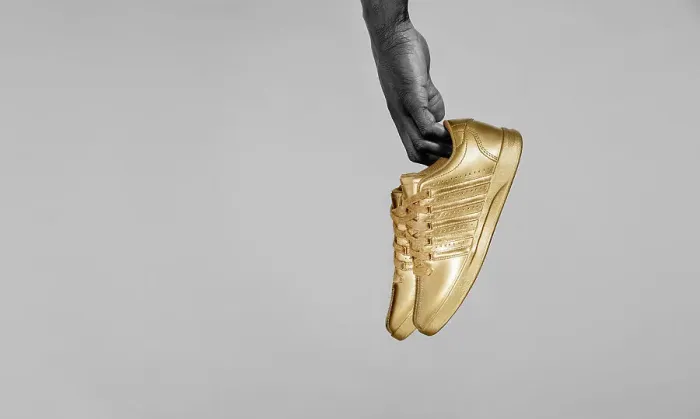 Framed Print : Yes. Desaturated / detail shot of Black man's hand holding gold painted sneakers Framed Print : Yes. Desaturated / detail shot of Black man's hand holding gold painted sneakers