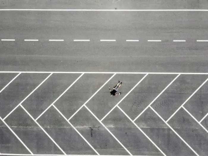 Framed Print : Drone view of man lying on back in empty parking lot Framed Print : Drone view of man lying on back in empty parking lot