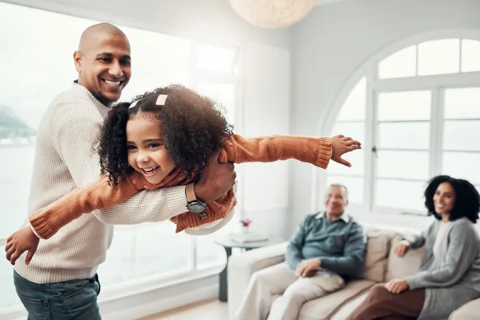 Framed Print : Family, flying and a father playing with his daughter in the living room of their home together during a visit
