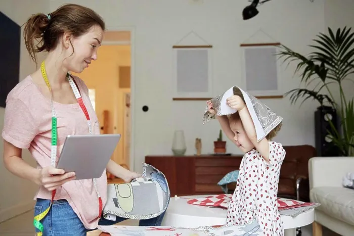 Framed Print : Fashion designer with digital tablet looking at playful daughter holding textile Framed Print : Fashion designer with digital tablet looking at playful daughter holding textile