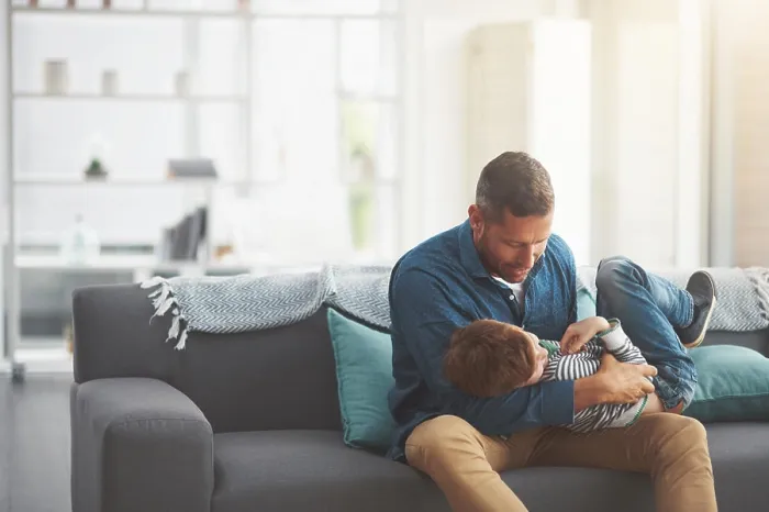 Framed Print : Father, boy and tickle kid on sofa together in home