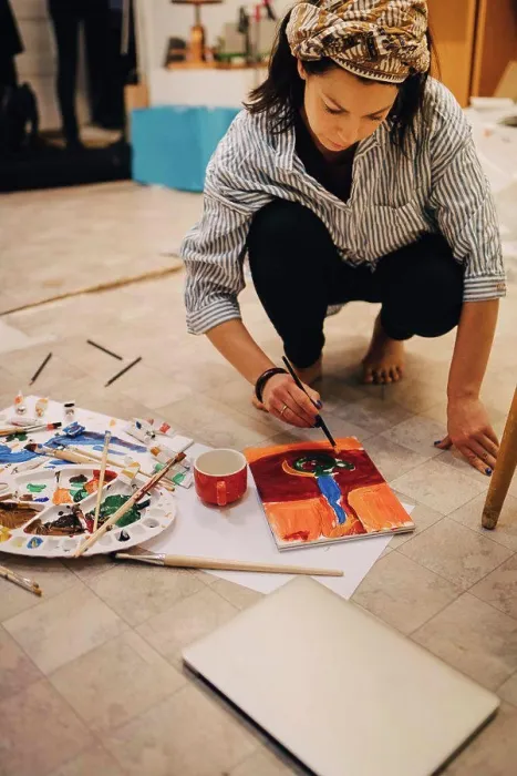 Framed Print : Female artist painting on paper while crouching at art studio Framed Print : Female artist painting on paper while crouching at art studio