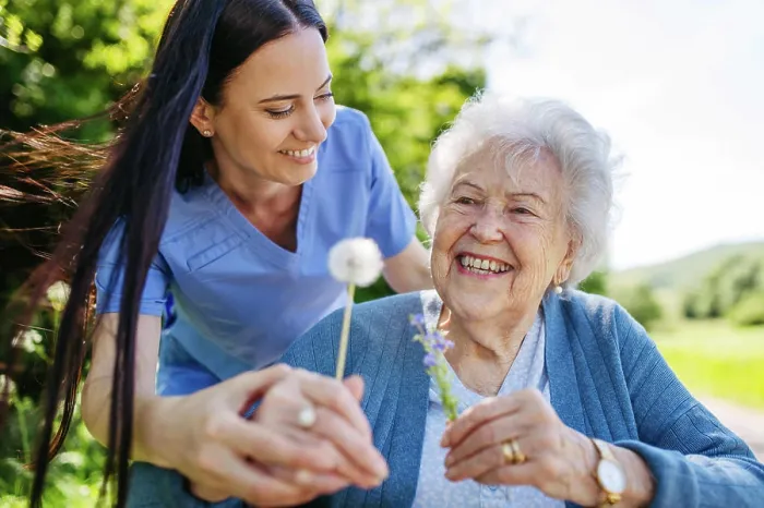 Framed Print : Female caregiver and senior woman in wheelchair holding dandelion