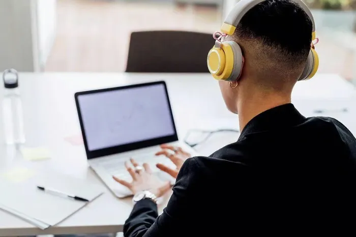 Framed Print : Female entrepreneur with headphones working on laptop in office Framed Print : Female entrepreneur with headphones working on laptop in office