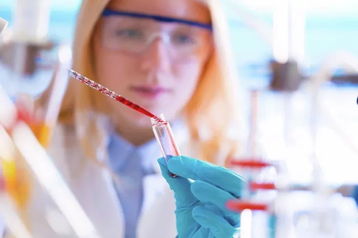 Framed Print : Female lab technician dripping chemical into test tube with pipette Framed Print : Female lab technician dripping chemical into test tube with pipette