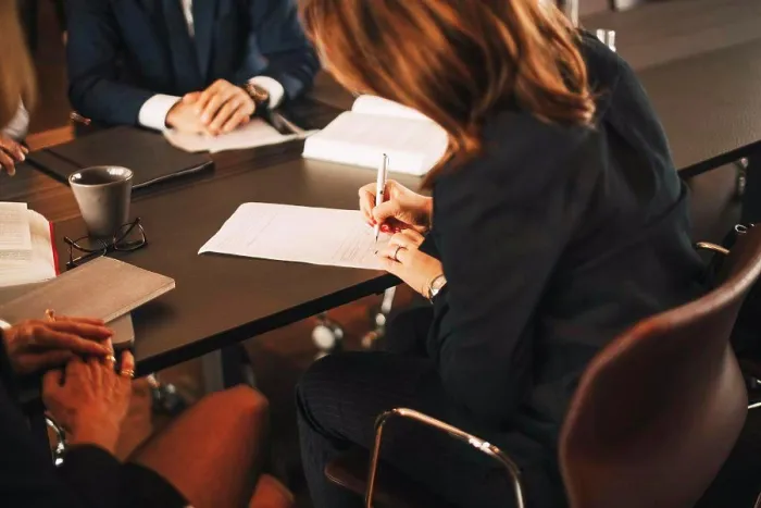Framed Print : Female lawyer signing documents while sitting in meeting with colleagues at office Framed Print : Female lawyer signing documents while sitting in meeting with colleagues at office