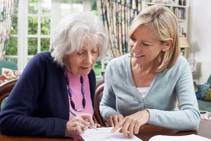 Framed Print : Female Neighbor Helping Senior Woman To Complete Form Framed Print : Female Neighbor Helping Senior Woman To Complete Form
