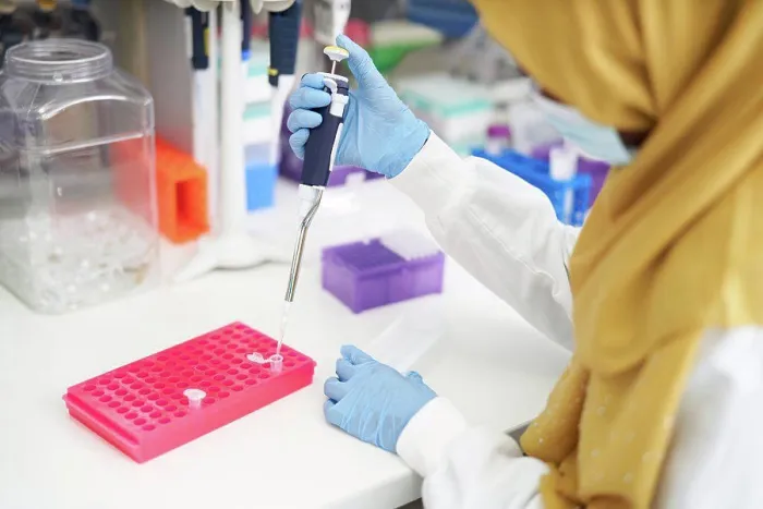 Framed Print : Female scientist in hijab and face mask filling pipette tray in laboratory