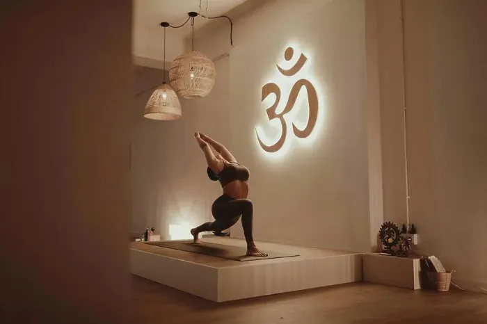 Framed Print : Female yoga instructor with arms raised bending while practicing by Om symbol