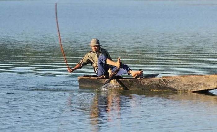 Framed Print : Fishermen in a wooden fishing boat using the traditional stick blow method Framed Print : Fishermen in a wooden fishing boat using the traditional stick blow method