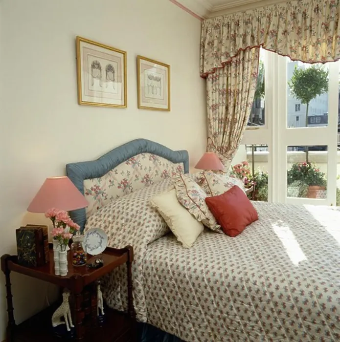 Framed Print : Floral curtains and toning quilt and upholstered headboard in traditional bedroom