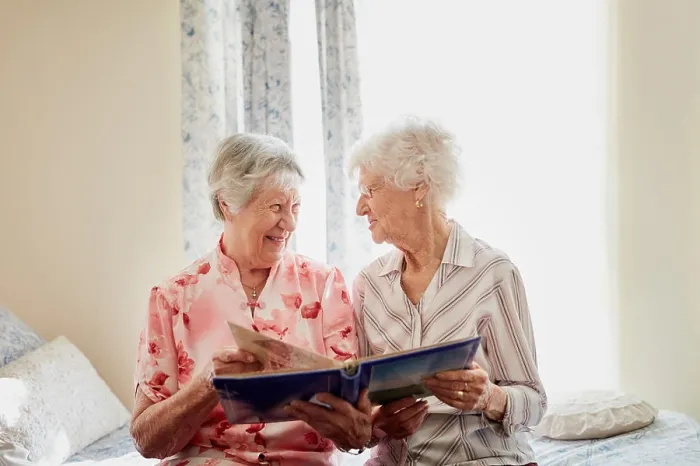 Framed Print : Friends, photo album and happy senior women on bed with memory
