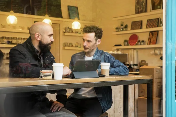 Framed Print : Friends sitting in window of cafe with tablet Framed Print : Friends sitting in window of cafe with tablet