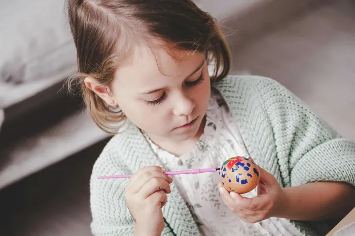 Framed Print : Girl coloring chicken egg at table Framed Print : Girl coloring chicken egg at table